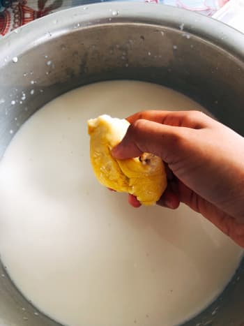 In a large pan, combine the coconut milk and durian flesh into the pan. Use your hand to remove the durian flesh from the seed.