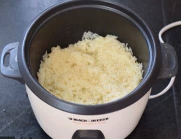 Add 3 cups uncooked rice to your rice cooker, rinse then fill with water to the appropriate fill line designated by your cooker. Add chicken bouillon cube and cook.