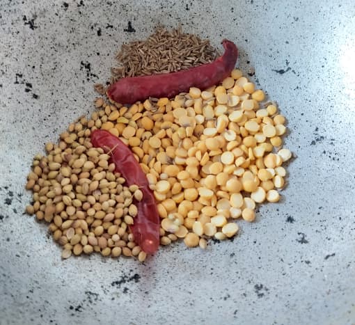 In a pan, dry-roast the chana dal or Bengal gram, dry red chilies, coriander seeds and cumin seeds over medium to low flame. Take care not to burn the spices.