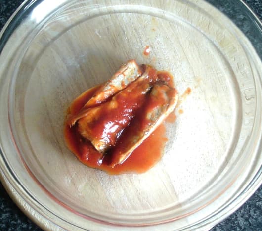 Canned sardines in tomato sauce are emptied in to a large bowl