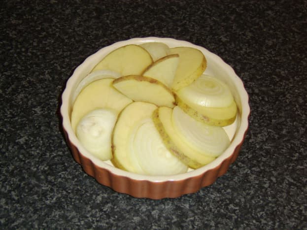 Potato and onion slices laid alternately in a baking dish