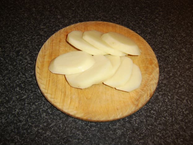 Potatoes are peeled and sliced to a thickness of half an inch for making fritters.