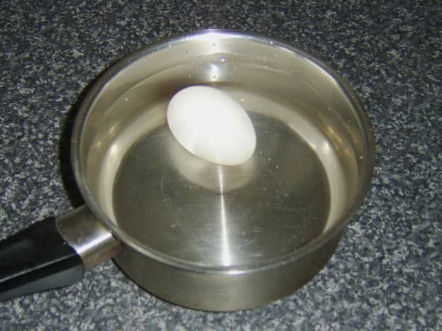 Duck egg is added to a pot of cold water for boiling