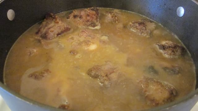 After browning, oxtails are covered with hot water and simmered for several hours.