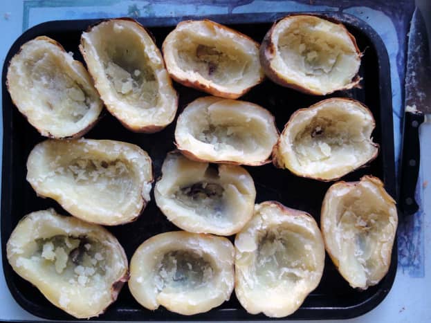 After potatoes are baked, cut in half and scoop out the potatoes to leave the skins.