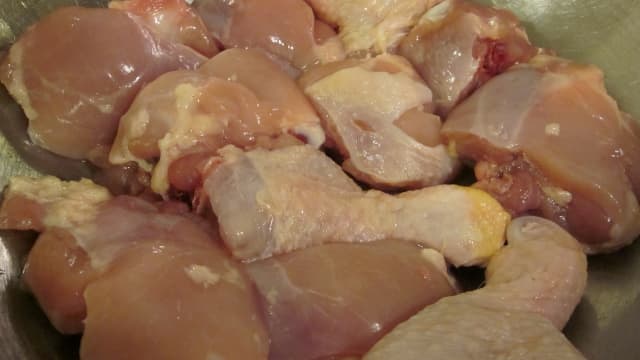 Washed and cut-up chicken legs are prepared for seasoning.