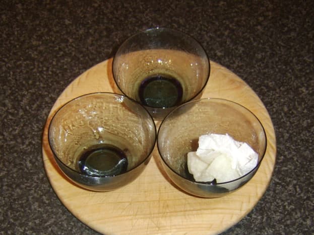 Small glass bowls are oiled for receiving cracked quail eggs