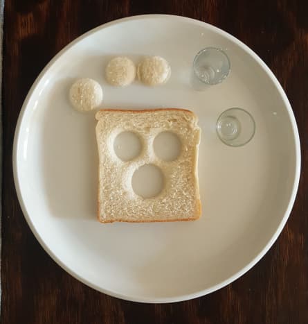 Cut out 3 circles in the shape of eyes and a nose in a slice of bread.