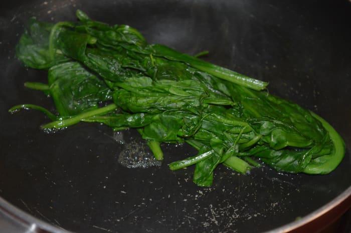 Step one: Saute the spinach leaves until they wilt. Hold them tight and chop into 1-inch pieces.