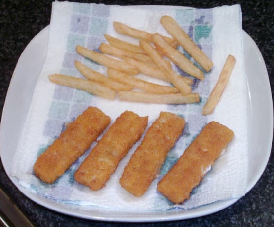 Fish fingers and chips are drained on kitchen paper