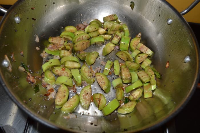 Step one: Heat oil in a deep-bottomed pan. Add mustard seeds. Let them pop up. Throw in eggplant cubes and curry leaves. Add some salt. Stir-cook them as per instructions.