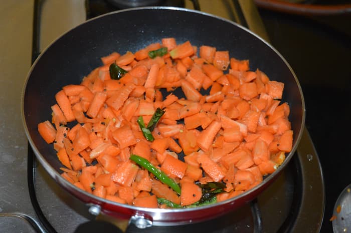 Step one: Make tempering with oil, mustard seeds, slit green chilies, and curry leaves as per instructions. Add chopped carrots.