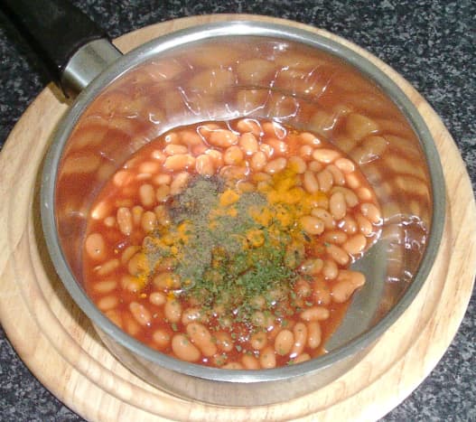 Additional seasonings are added to baked beans in tomato sauce