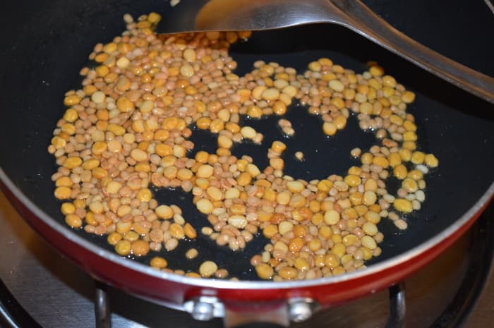 Saut&eacute; split chickpea (gram dal) and white lentil (urad dal) in oil until they get lightly golden brown.