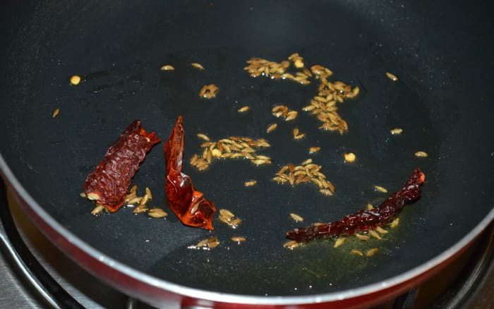 Step one: Heat ghee or oil in a deep-bottomed pan. Throw in cumin seeds. Let them crackle. Add broken dry red chilies. Saute for five seconds.
