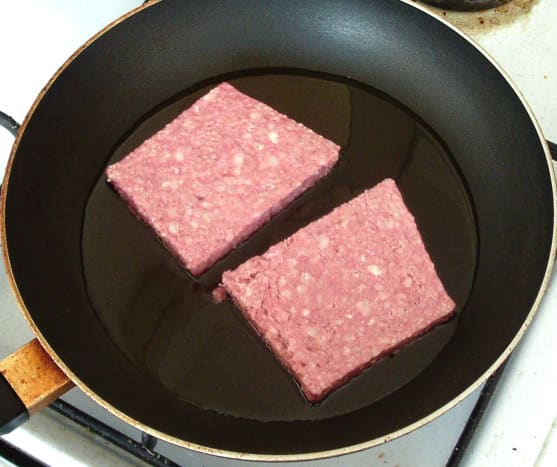 Sliced sausages are added to hot frying pan