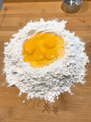 Form a well in the middle of the flour. Crack the eggs in the middle of the well.