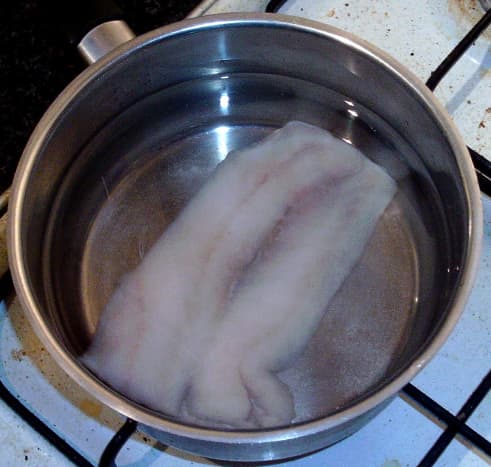 Gently poaching pollack fillet in water