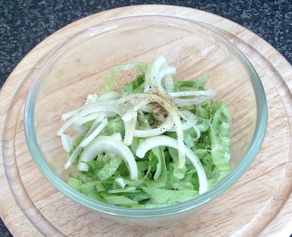 Sliced lettuce and onion are seasoned and combined