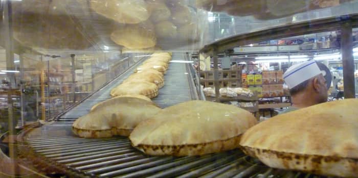 Pita bread coming down the conveyor belt inside of the store