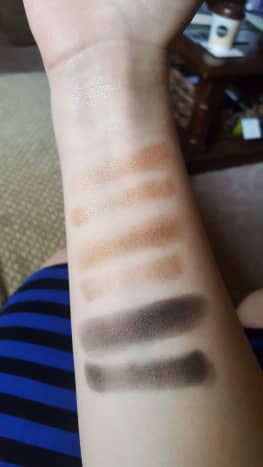 Finger and brush swatches of the left column of shadows from the Wet N Wild Comfort Zone palette, starting with the pale shimmery yellow, which is a bit hard to see on my skin
