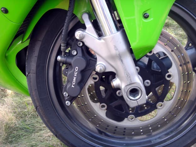 Location of the brake caliper; on the rear side of the front wheel.