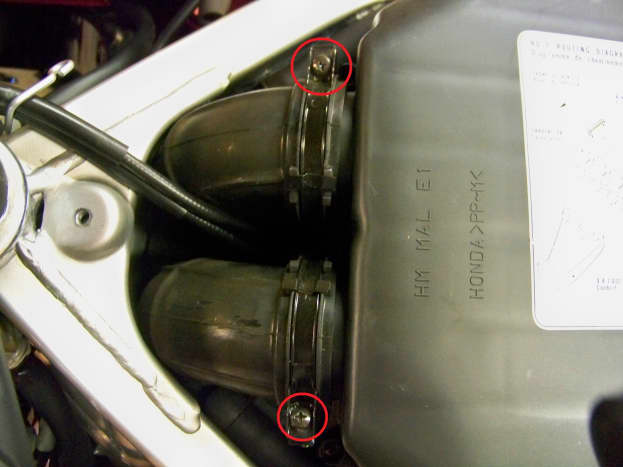 Loosen screws on air duct clamps (circled in red), disconnect air duct hoses from the air cleaner cover.