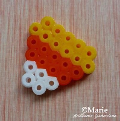 Make some tiny candy corn designs with fused Perler beads for Halloween and turn them into charms, necklaces, or even little earrings.