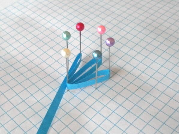 Arrange six pins in a circle and wrap a strip of paper around each pin.