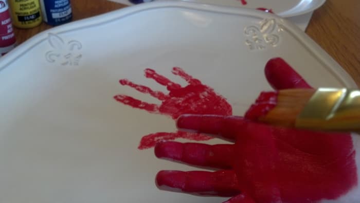 Paint your child's entire hand (after it's been washed!) with ceramic paint and press it firmly onto the platter. 
