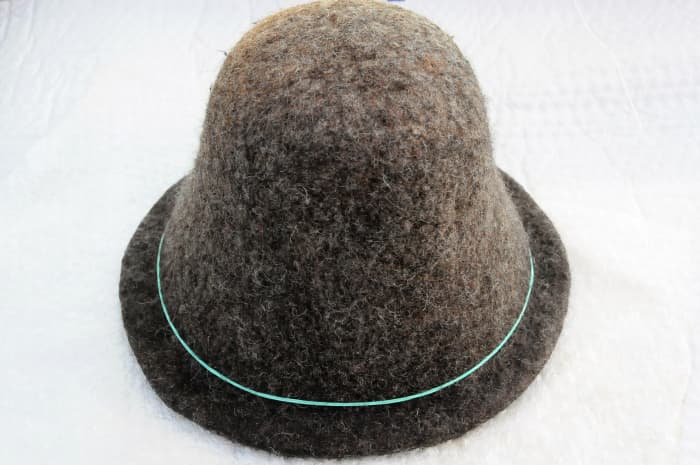 Put the hat onto the hat shaper, rub with hot soapy water, rinse and trim the brim