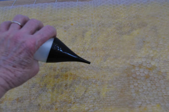 Wetting the bubble wrap to facilitate easy movement on the surface.