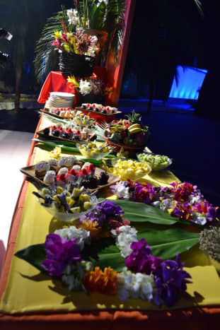 Buffet of food with lots of fruit and flowers for decoration