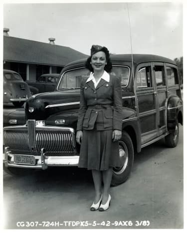 Woman standing in front of 1942 Ford Woodie during World War II