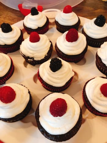 Moist chocolate cupcakes with vanilla frosting topped with fresh red raspberries and blackberries