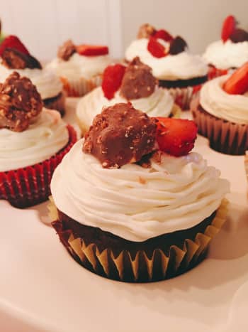 Scrumptious chocolate cupcake with vanilla frosting, freshly sliced strawberries, and Ferrero Rocher chocolate hazelnut