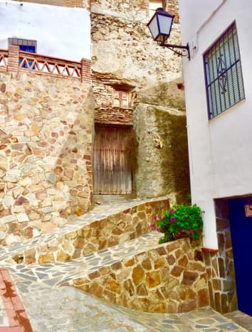 Street view from the upper part of the village, with steps and contrasting walls of rough stone against whitewashed walls.