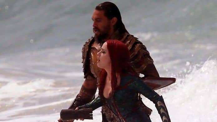 Jason Mamoa and Amber Heard in Aquaman emerge from the ocean.