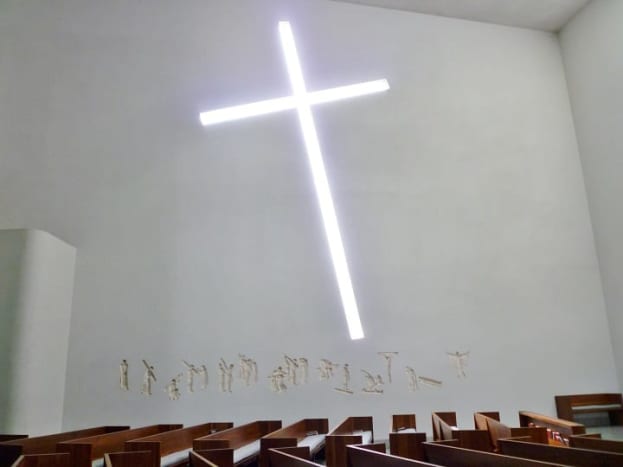 Interior view of the chapel with glass cross cutout &amp; concave stations of the cross