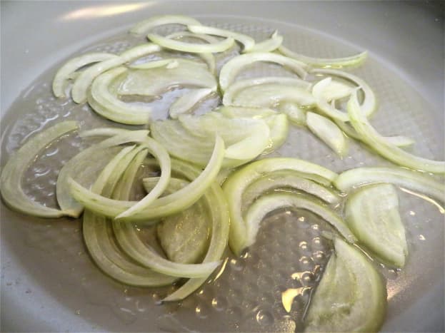 Sliced onions in a pan with olive oil