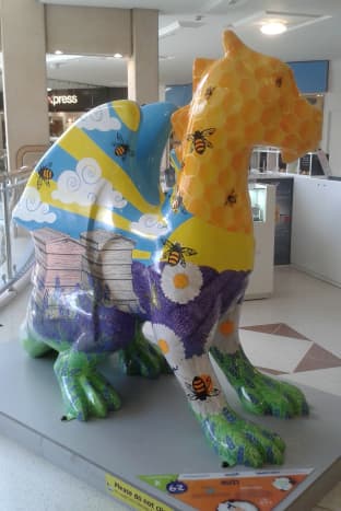 Buzz, depicting bee hives, bees in the sky with clouds and sunbeams, honeycomb, lavender &amp; daisies.  Designed to reflect the beauty of the Norfolk countryside, she stands in the shopping mall.