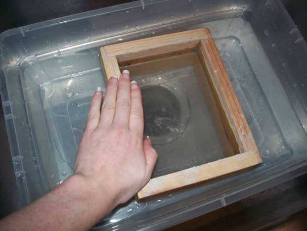 Step 4: Hold the deckle in the water with one hand.