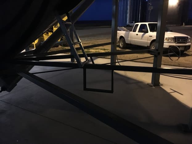 A step and short ladder are provided to access a manhole used for servicing the hopper when it is empty.