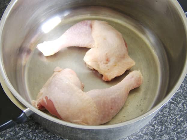 Whole chicken legs are laid in base of soup or stock pot