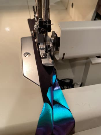 Cut your strip longer than you need and twice the width you want the neck strap. Sew right side together and turn right side out forming a flat tube.