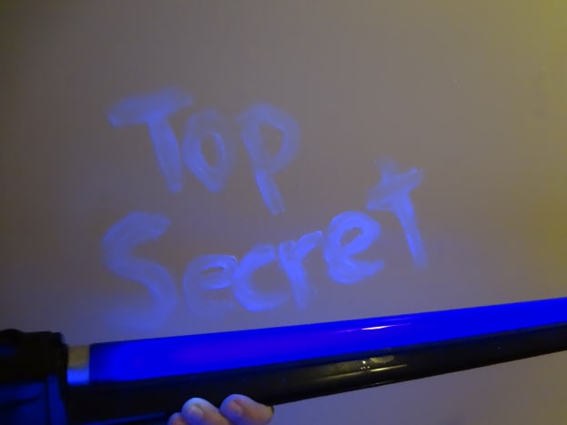 The message written in petroleum jelly glows under a blacklight.