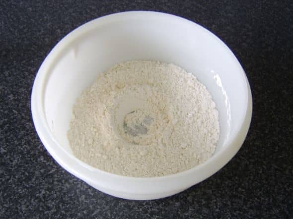 Flour, yeast and salt are mixed together in a bowl. A well is made in the centre where the water and olive oil will be added