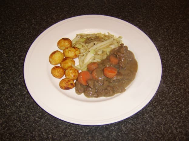 Venison stew with roasted potatoes, braised cabbage and onion