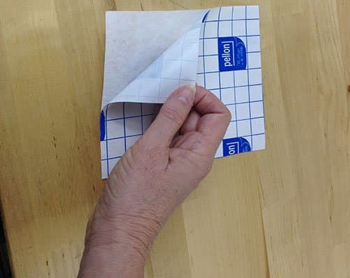 Cut a piece of adhesive stabilizer about an inch larger than the cap hoop. Pull the backing off.