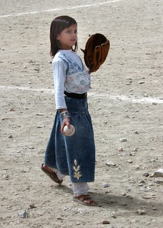 An Afghan girl plays with her baseball and glove at Camp Harriman. 